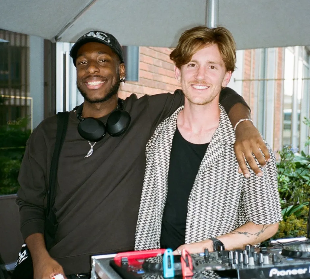 Two men behind a DJ booth at a local event